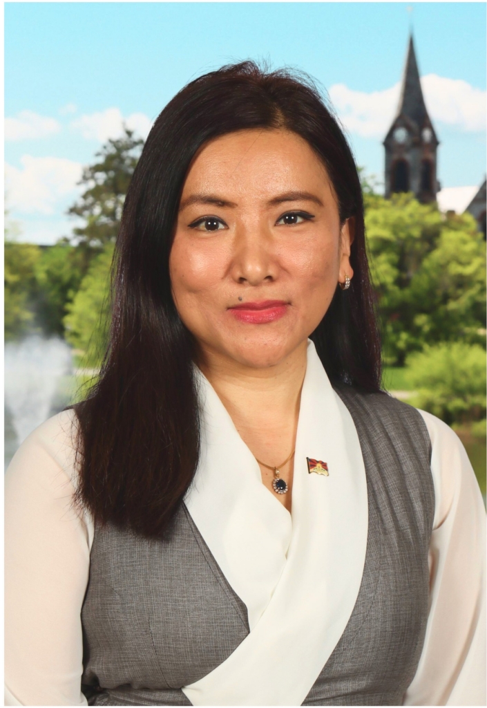 A smiling, forward-facing photo of an Asian woman with dark, straight hair, wearing a white collar and gray blazer.